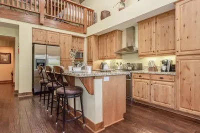 a large kitchen with wooden cabinets and bar stools at Lodges 1132 - 3 bedroom Townhome on Golf Course in Mammoth Lakes