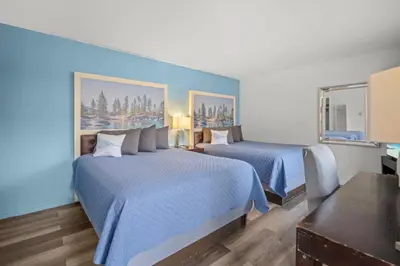 two beds in a hotel room with blue walls at Bluebird Day Inn & Suites in South Lake Tahoe