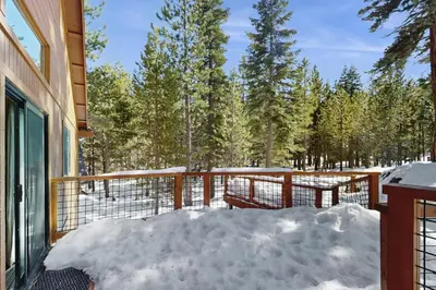 a snow covered porch with a fence and trees at Tuna Bush in Truckee