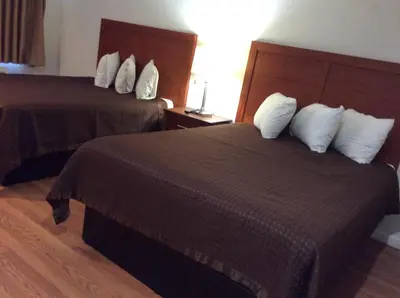 a hotel room with two beds with white pillows at La Plaza Inn in Los Banos