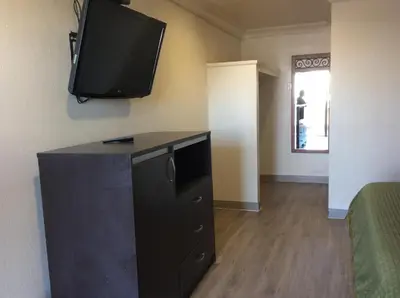 a room with a dresser with a tv on the wall at La Plaza Inn in Los Banos