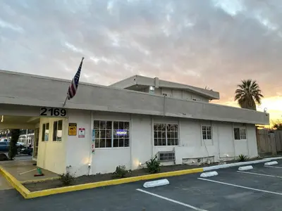 a building with an american flag in a parking lot at La Plaza Inn in Los Banos