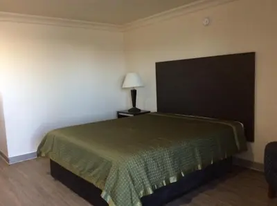 a hotel room with a bed and a lamp at La Plaza Inn in Los Banos