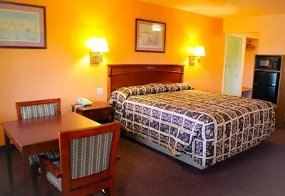 a hotel room with a bed and a table and chairs at Hawthorne's Best Inn in Hawthorne