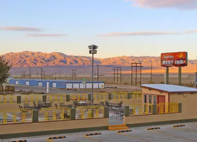 a motel in the desert with a sign and mountains at Hawthorne's Best Inn in Hawthorne