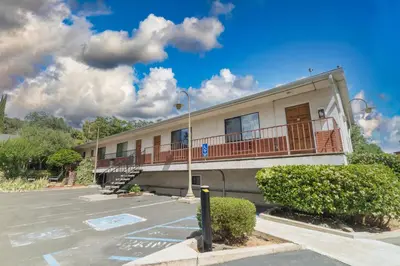 a building with a balcony and a parking lot at Mariposa Lodge in Mariposa