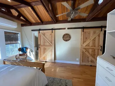 a bedroom with a barn door with a ceiling fan at Yosemite Basecamp in Groveland