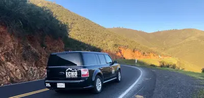 a black truck driving down a road at Yosemite Basecamp in Groveland