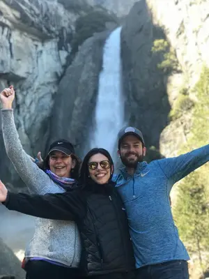 a group of three people standing in front of a waterfall at Yosemite Basecamp in Groveland