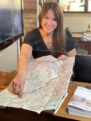 a woman sitting at a table holding a map at Yosemite Basecamp in Groveland
