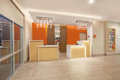 a store lobby with orange walls and wooden counters at La Quinta by Wyndham Madera in Madera