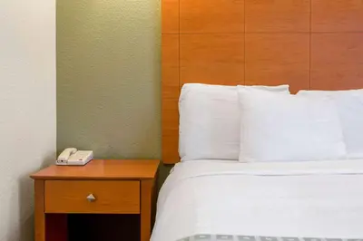 a hotel room with a bed and a phone on a table at La Quinta by Wyndham Tulare in Tulare