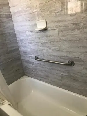 a white bath tub in a bathroom with a tile wall at Western Holiday Lodge in Three Rivers
