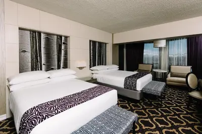 a hotel room with two beds and a chair at Harrah's Lake Tahoe, A Caesars Destination in Stateline