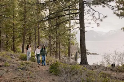 a group of three people walking down a trail near the water at Caesars Republic Lake Tahoe, A Caesars Destination in Stateline