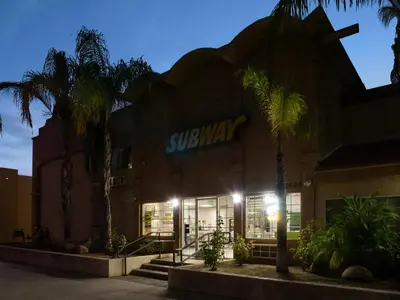 a building with palm trees in front of a store at Dream Inn in Fresno