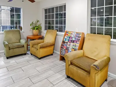 a waiting room with chairs and a table and windows at Dream Inn in Fresno