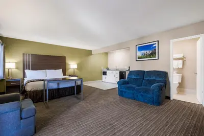 a hotel room with a bed and blue chairs at Heritage Inn - Yosemite/Sonora in Sonora
