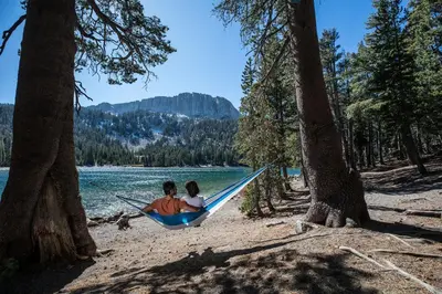 two people in a hammock on a beach with trees at Aspen Creek #311 condo in Mammoth Lakes