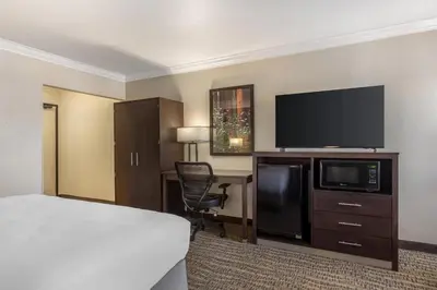 a hotel room with a bed and a desk with a television at Best Western Town & Country Lodge in Tulare