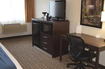 a hotel room with a desk and a television on a dresser at Best Western Town & Country Lodge in Tulare