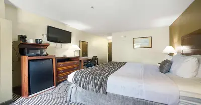 a hotel room with a bed and a flat screen tv at SureStay Plus Hotel by Best Western Rocklin in Rocklin