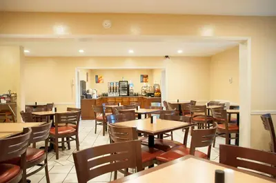 a restaurant with tables and chairs and a kitchen at Best Western Village Inn in Fresno
