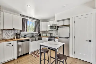 a kitchen with white cabinets and a table and two stools at The Historic West Walker Motel in Walker