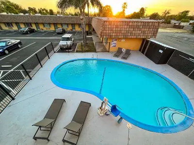 a swimming pool at a hotel with chairs and a parking lot at Rodeo Lodge in Clovis