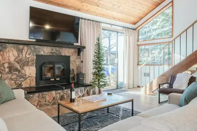a living room with a stone fireplace with a tv at Snowflower 12 in Mammoth Lakes
