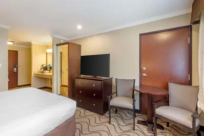 a hotel room with a bed and a desk and a tv at Best Western Plus Orchid Hotel & Suites in Roseville