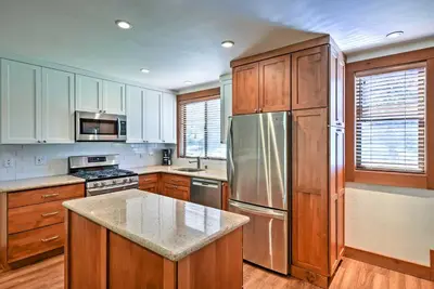 a kitchen with wooden cabinets and a stainless steel refrigerator at Modern Condo with Balcony - Walk to Northstar Lifts! in Truckee