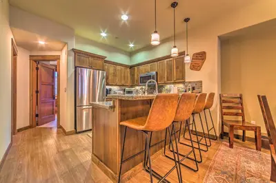 a kitchen with wooden cabinets and bar stools at Central Mammoth Lakes Townhome about 1 Mi to Slopes in Mammoth Lakes