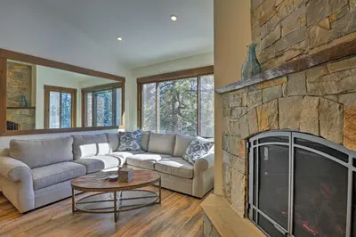 a living room with a couch and a stone fireplace at Walk to Ski Shuttle Truckee Condo with Hot Tub in Truckee