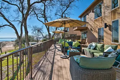 a wooden deck with chairs and an umbrella at Casa dAmore Extravagant Lakefront Villa! in Granite Bay