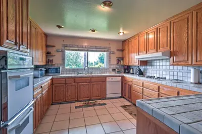 a large kitchen with wooden cabinets and white appliances at 7 Mi to Dtwn Gilroy Spacious Home on 20 Acres! in Gilroy