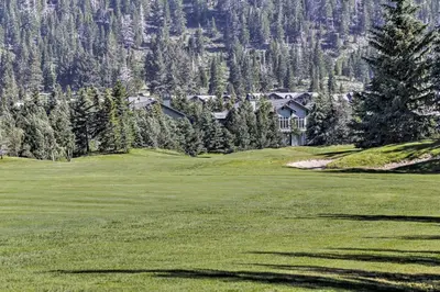 a golf course with a house in the mountains at Mammoth Lakes Vacation Rental with Community Hot Tub in Mammoth Lakes