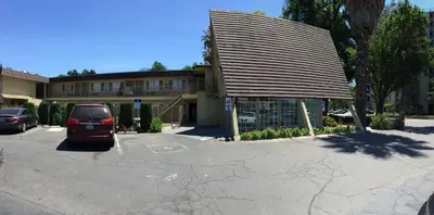 a car parked in a parking lot in front of a building at Discovery Inn in Modesto