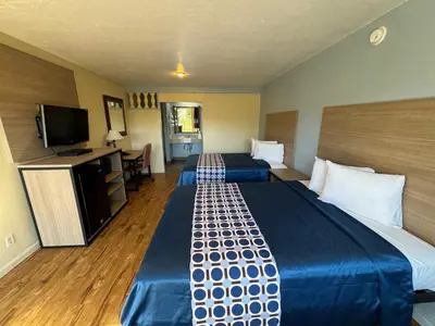 a hotel room with two beds and a flat screen tv at Discovery Inn in Modesto