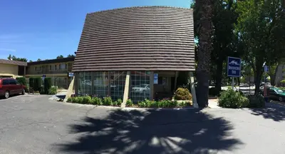 a building with a gambrel roof on a street at Discovery Inn in Modesto