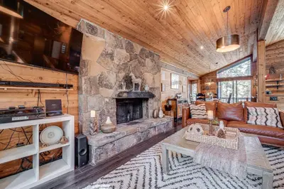 a living room with a large stone fireplace at Free Ski Shuttle! Spacious Northstar Resort Cabin in Truckee