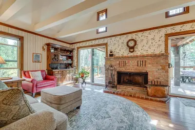 a living room with a fireplace and a red couch at Rustic Riverfront Truckee Cabin with Deck and BBQ in Truckee