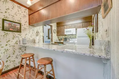 a kitchen with a counter and two stools at Rustic Riverfront Truckee Cabin with Deck and BBQ in Truckee