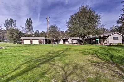 a yard with a house and a grass field at Cozy Home with Patio Near Yosemite National Park! in Mariposa