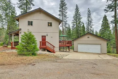 a large white house with a garage and a driveway at 4 Mi to Pine Lake Hathaway Pines Cabin with Deck in Hathaway Pines