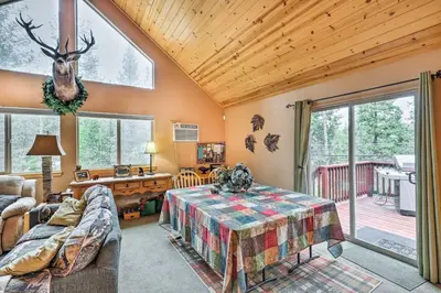 a living room with a table and a large window at 4 Mi to Pine Lake Hathaway Pines Cabin with Deck in Hathaway Pines