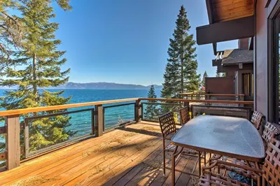 a deck with a table and chairs and the water at 11 Mi to Palisades Tahoe Lakefront Home with View! in Tahoe City