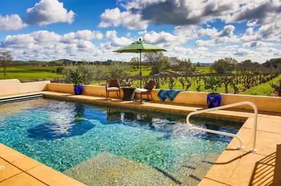 a swimming pool with chairs and an umbrella at Working Vineyard and Private Pool Villa in Plymouth in Plymouth