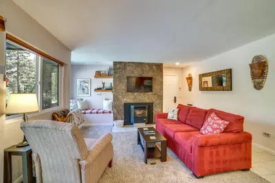 a living room with a red couch and a fireplace at Quiet Condo with Great Views, half Mi to Eagle Lodge! in Mammoth Lakes