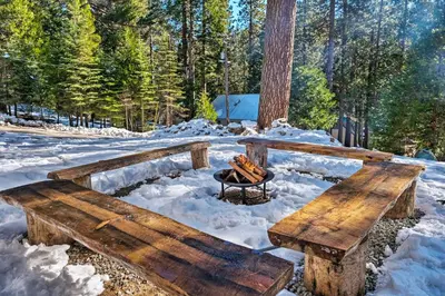 a wooden bench with a fire in the snow at Strawberry Hill Cabin 5 Mi to Skiing and Lake in Strawberry